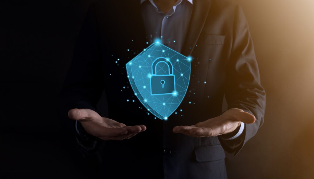 Businessman holding a digital shield with a glowing padlock icon, symbolizing cybersecurity, data protection, and network security.
